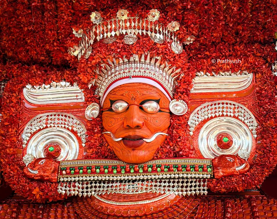 Muchilottu Bhagavathi mudi and face, framed by thechi flowers