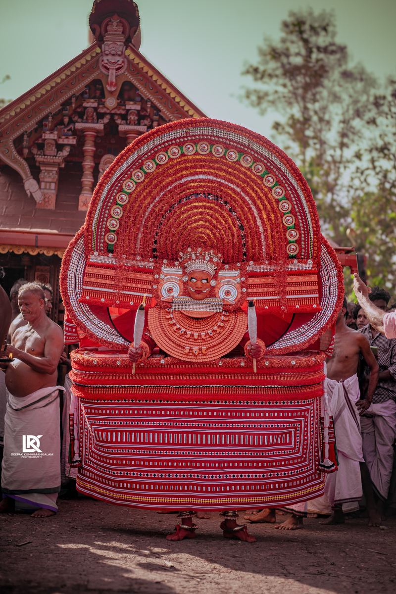 The Bhagavathi theyyam in full costume before the kavu, surrounded by devotees
